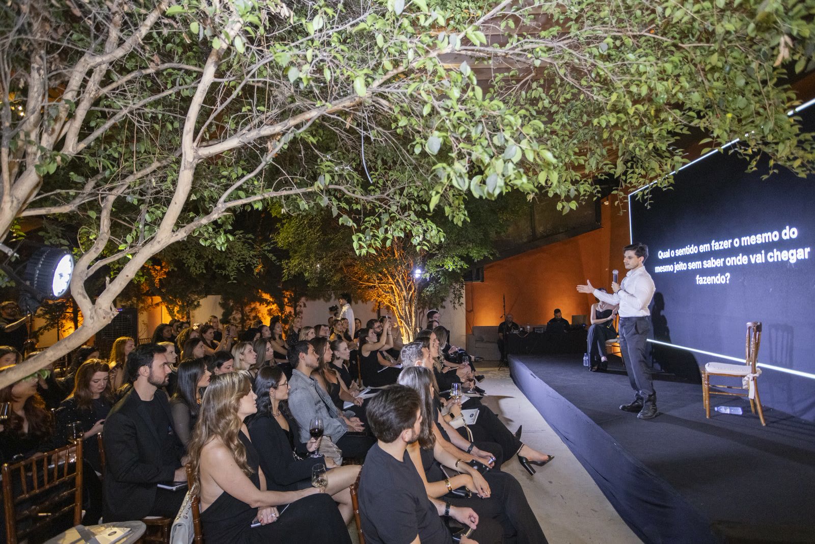 Leonardo Rosso no palco ao ar livre, sob as árvores, com a plateia sentada à frente
