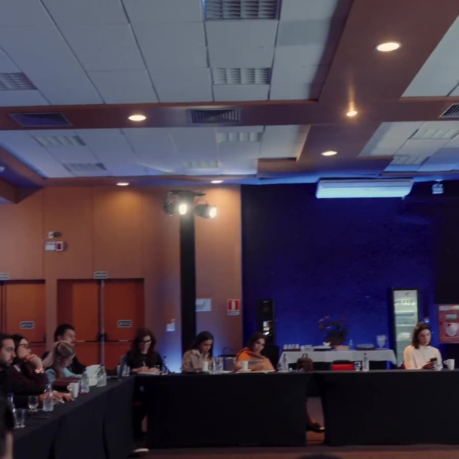 Sala do encontro com os participantes sentados em mesas em U