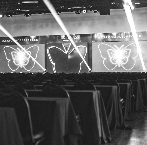 Evento First Class Reconecta · palco com borboletas em neon e plateia